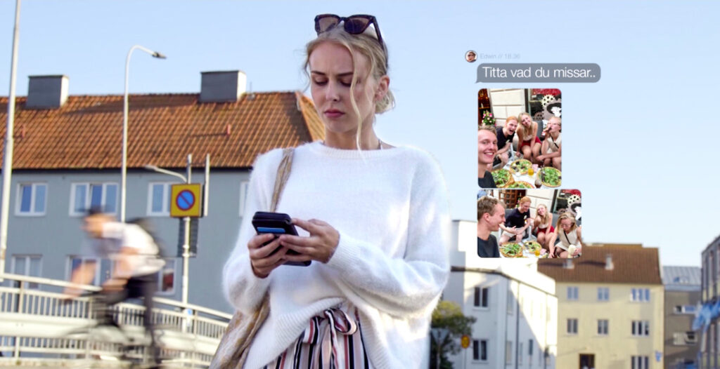 En ung kvinna tittar i sin mobil.