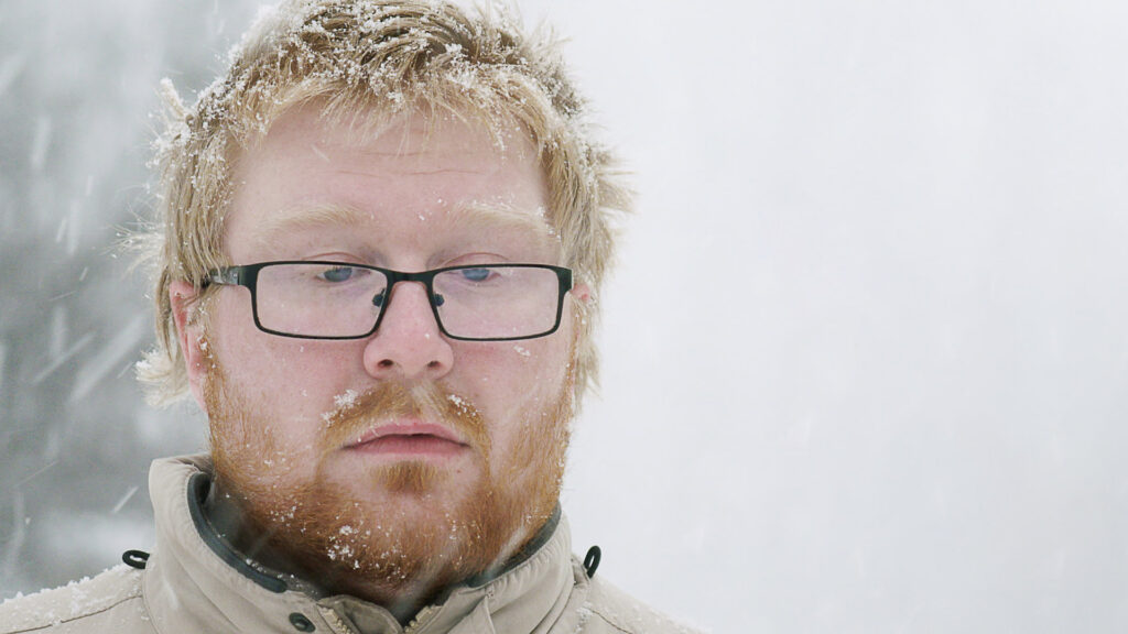 En kille med ledset ansiktsuttryck och snö i håret.